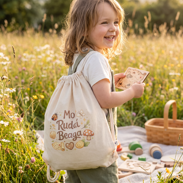 Child wearing the Mo Rudaí Beaga organic cotton drawstring bag in a wildflower meadow