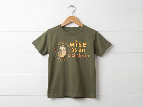 olive kids t-shirt with owl design hanging on wooden shiplap wall