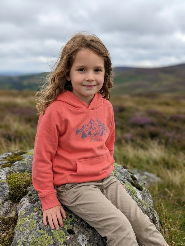 Child wearing orange hoodie with mountain design, portrait