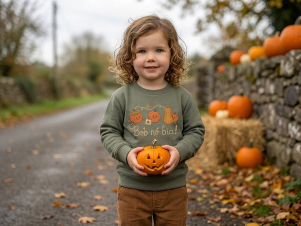 Child wearing olive sweatshirt with pumpkins design, portrait