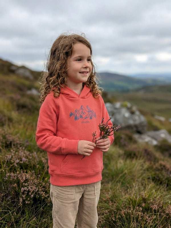 Child wearing orange hoodie with mountain design, portrait