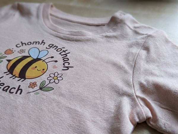 Close-up detail of bee illustration on peach t-shirt