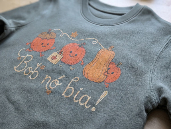 Close-up detail of pumpkins illustration on olive sweatshirt