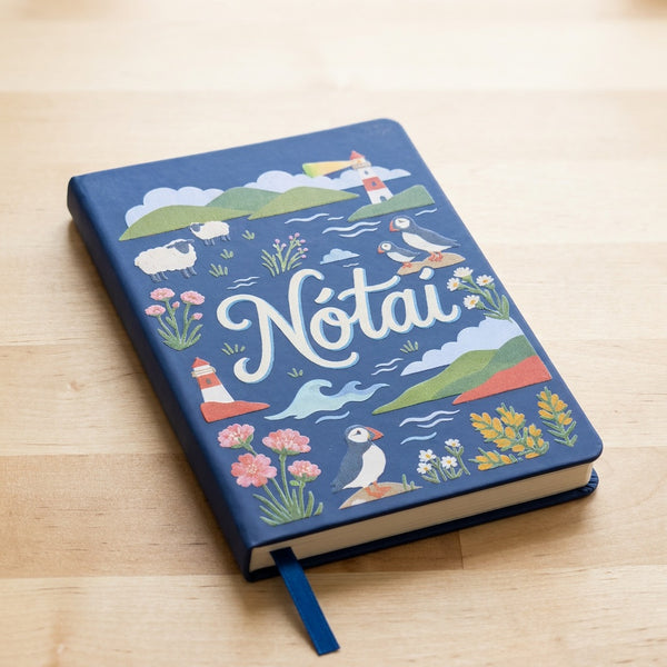 Close-up of the navy Nótaí cover: puffins, sheep, a lighthouse, sea thrift and gorse