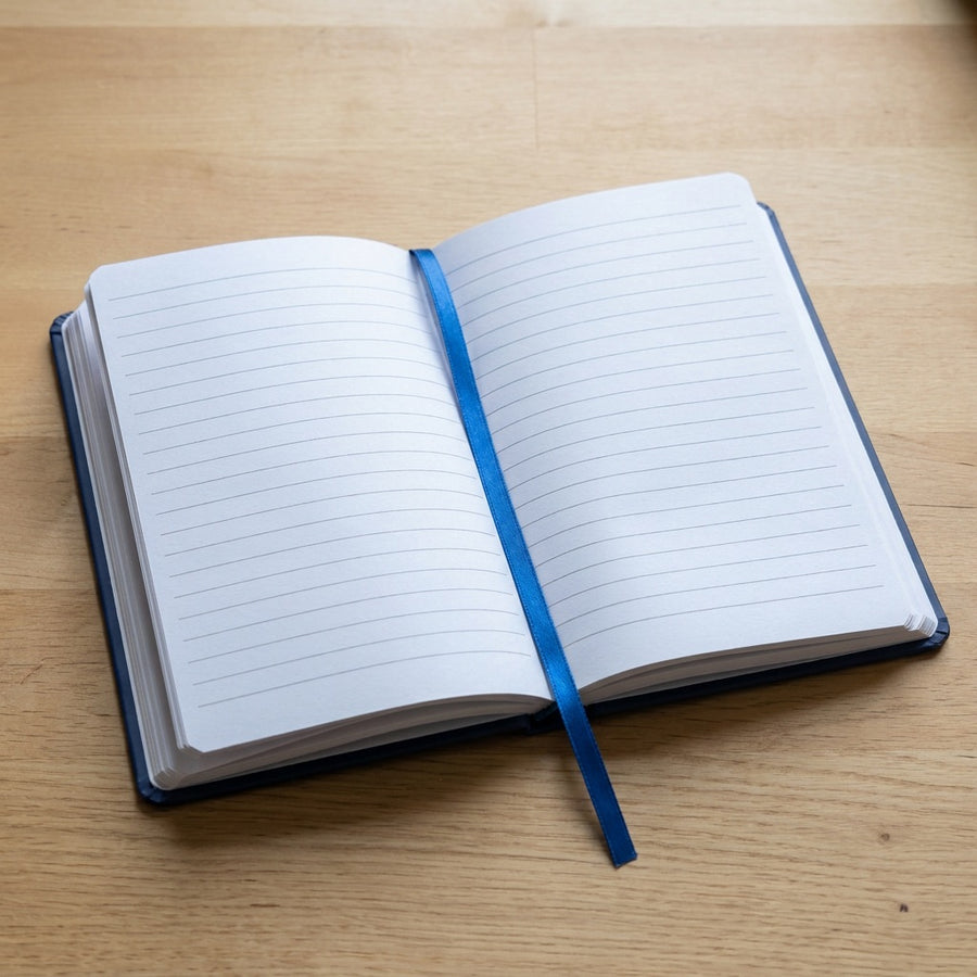 The Nótaí notebook lying open, showing the lined sheets and ribbon marker