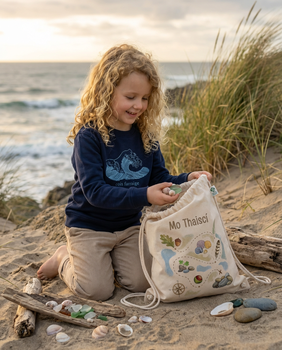 Girl collecting beach treasures with Mo Thaiscí bag, wearing Glasóg Cois Farraige sweatshirt