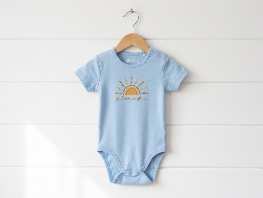 blue kids bodysuit with sun design hanging on wooden shiplap wall
