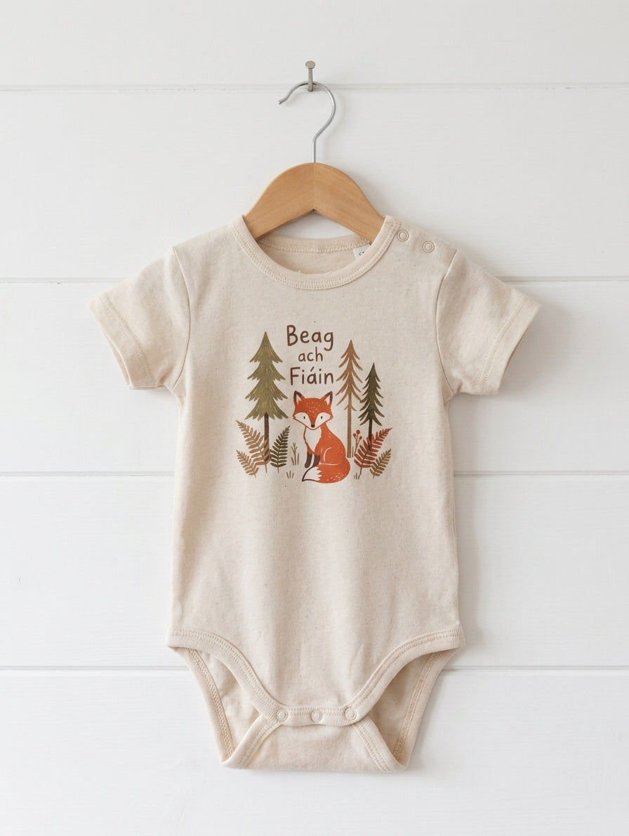cream kids bodysuit with beagfiain design hanging on wooden shiplap wall