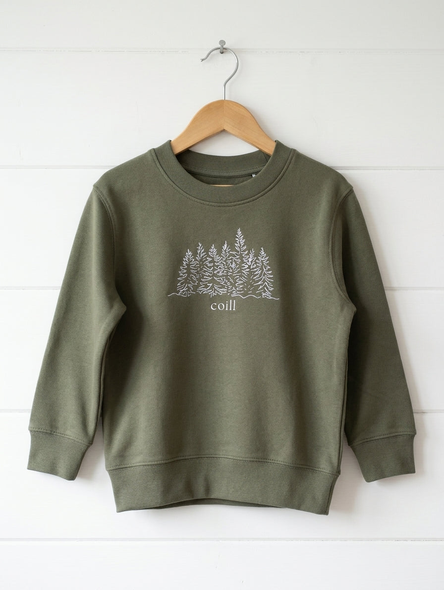 olive sweatshirt with trees design hanging on wooden shiplap wall
