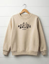 beige kids sweatshirt with mountain design hanging on wooden shiplap wall