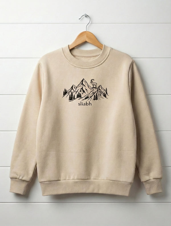 beige kids sweatshirt with mountain design hanging on wooden shiplap wall