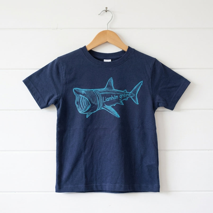 blue kids t-shirt with shark design hanging on wooden shiplap wall