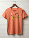 peach kids t-shirt with bee design hanging on wooden shiplap wall