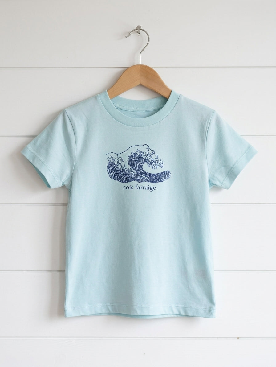 poolblue kids t-shirt with wave design hanging on wooden shiplap wall
