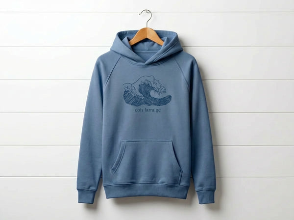 blue kids hoodie with wave design hanging on wooden shiplap wall
