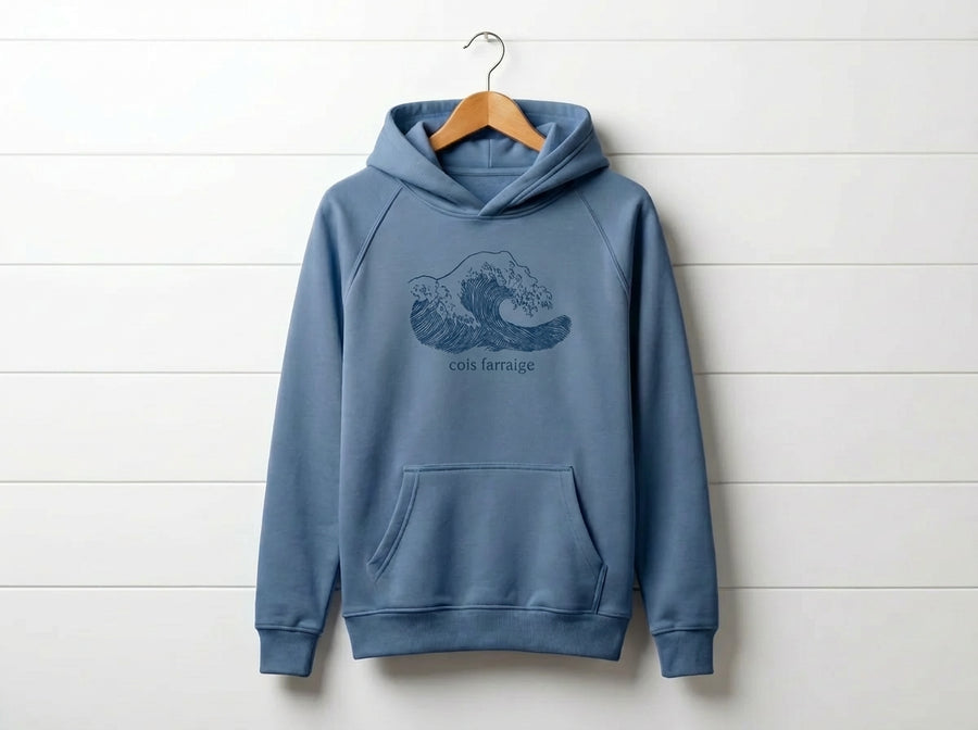 blue kids hoodie with wave design hanging on wooden shiplap wall