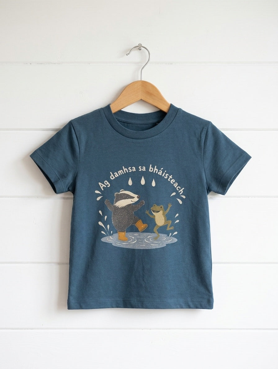 twilightblue kids t-shirt with badger-frog design hanging on wooden shiplap wall