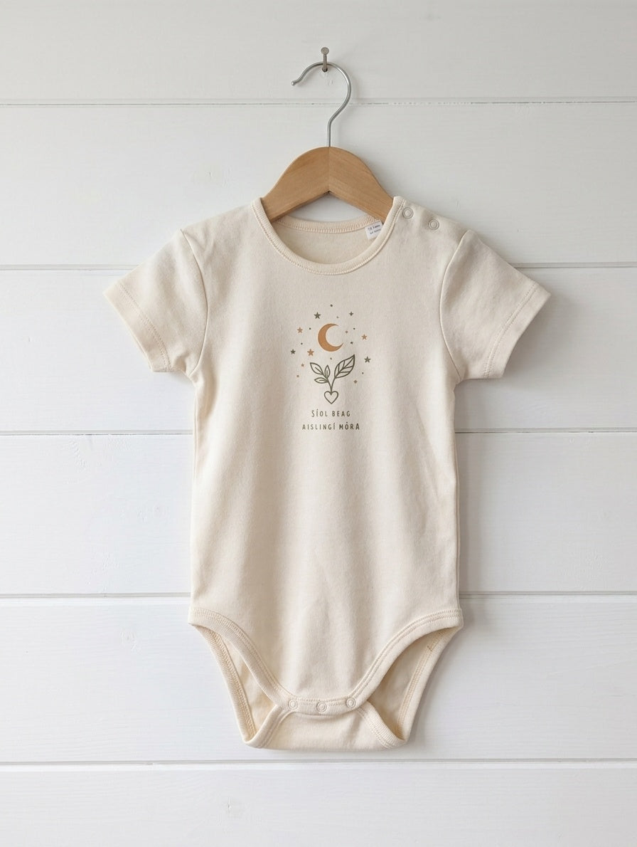 cream kids bodysuit with seeddreams design hanging on wooden shiplap wall