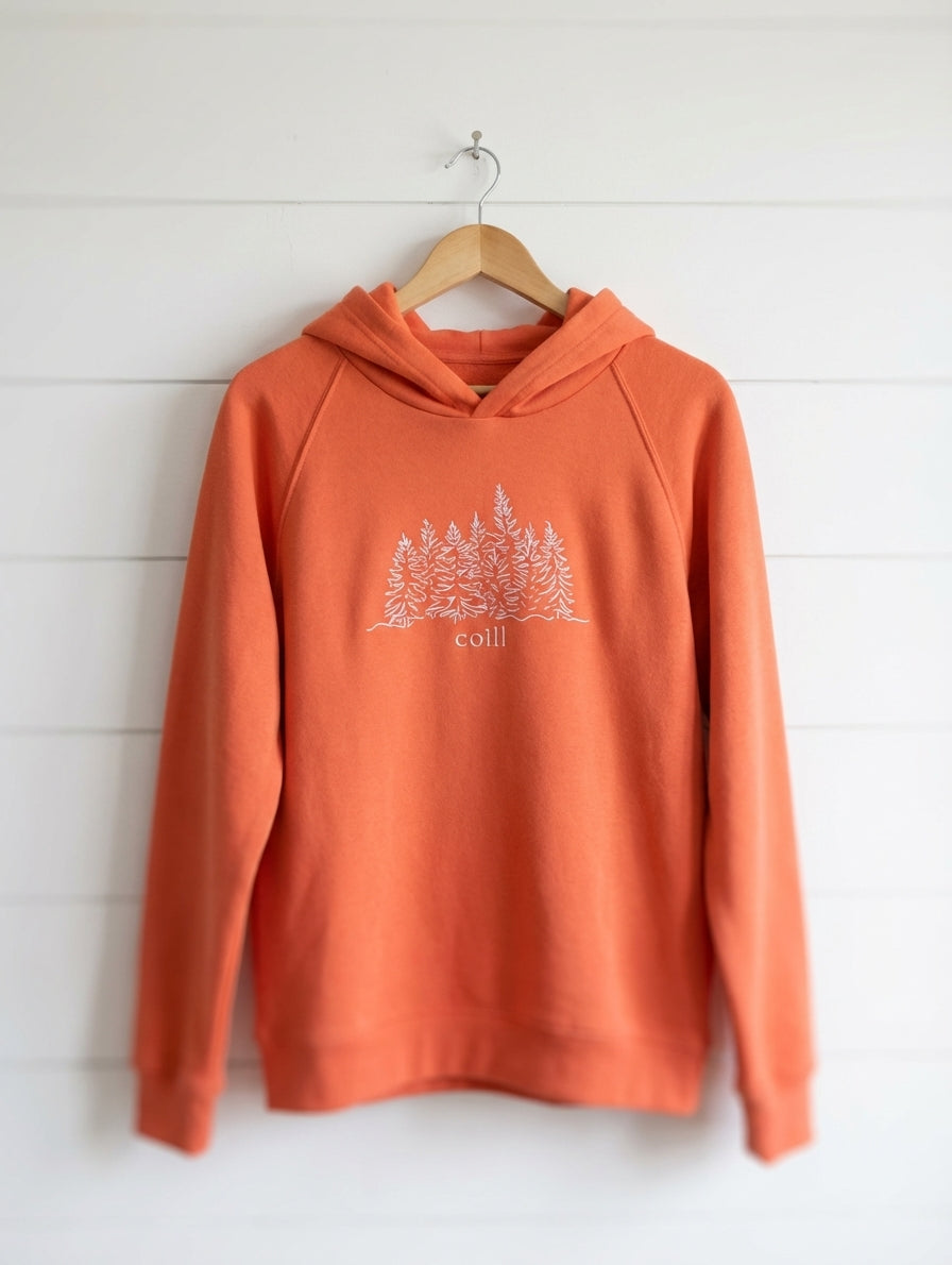 orange kids hoodie with trees design hanging on wooden shiplap wall
