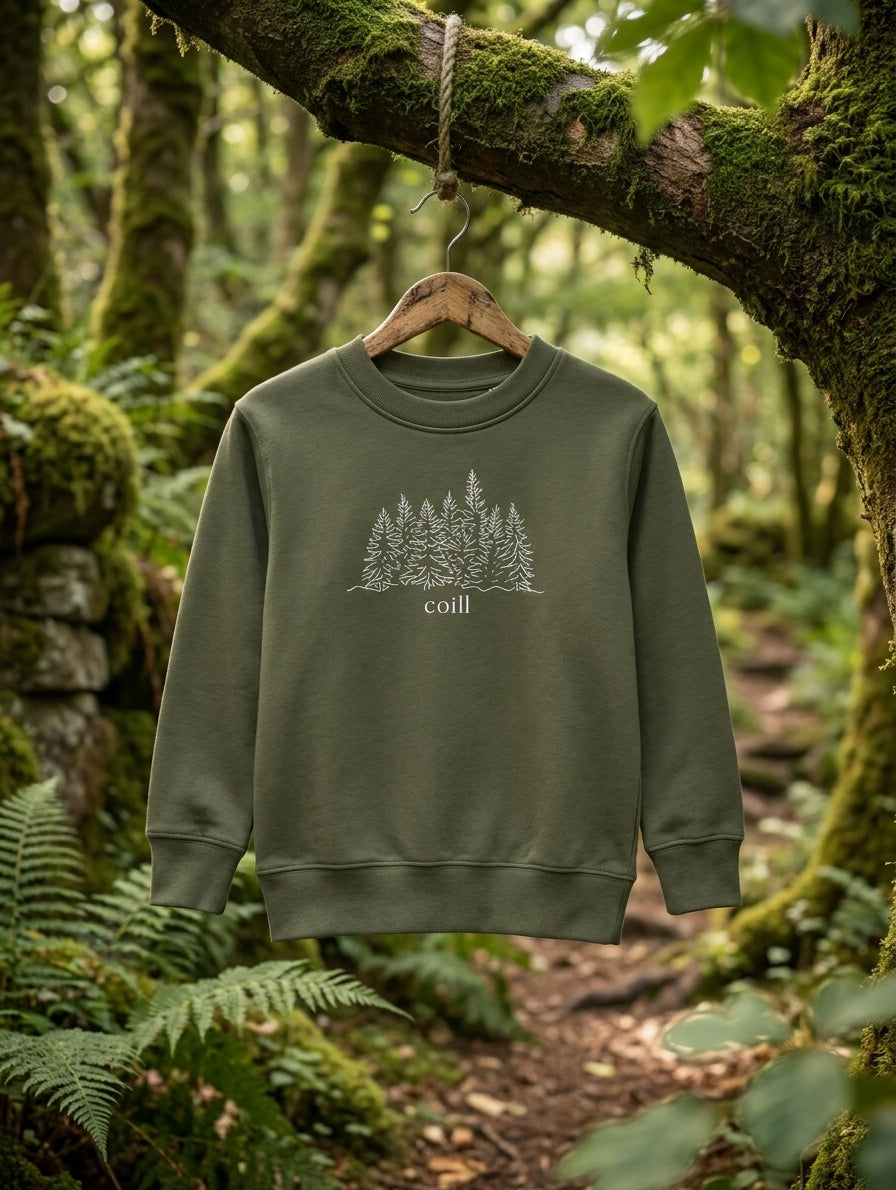 Olive Coill sweatshirt hanging on a wooden hanger in an Irish forest