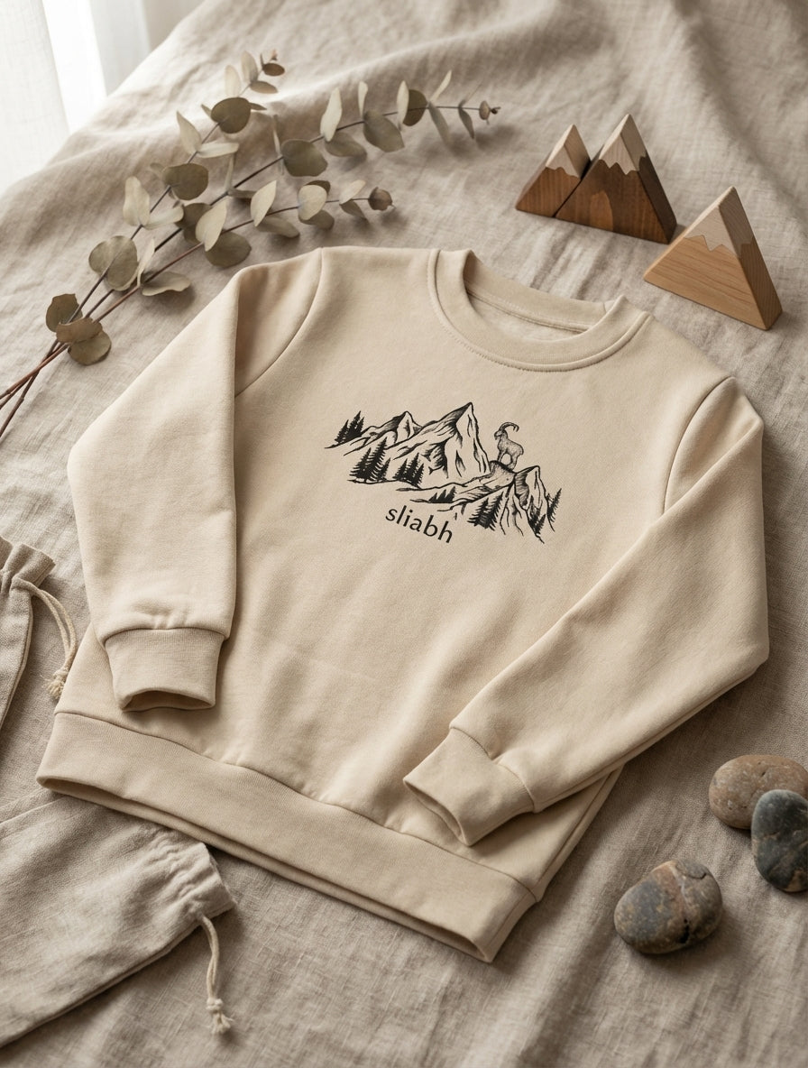 Flat lay of beige sweatshirt with mountain design on natural leaf background