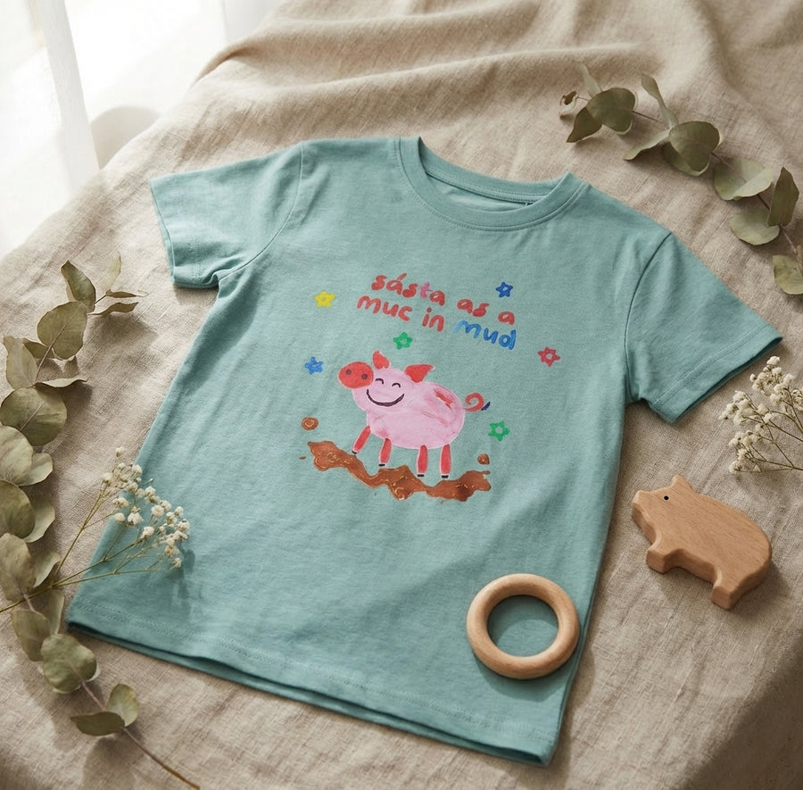Flat lay of teal t-shirt with pig design on natural leaf background