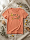 Flat lay of peach t-shirt with bee design on natural leaf background