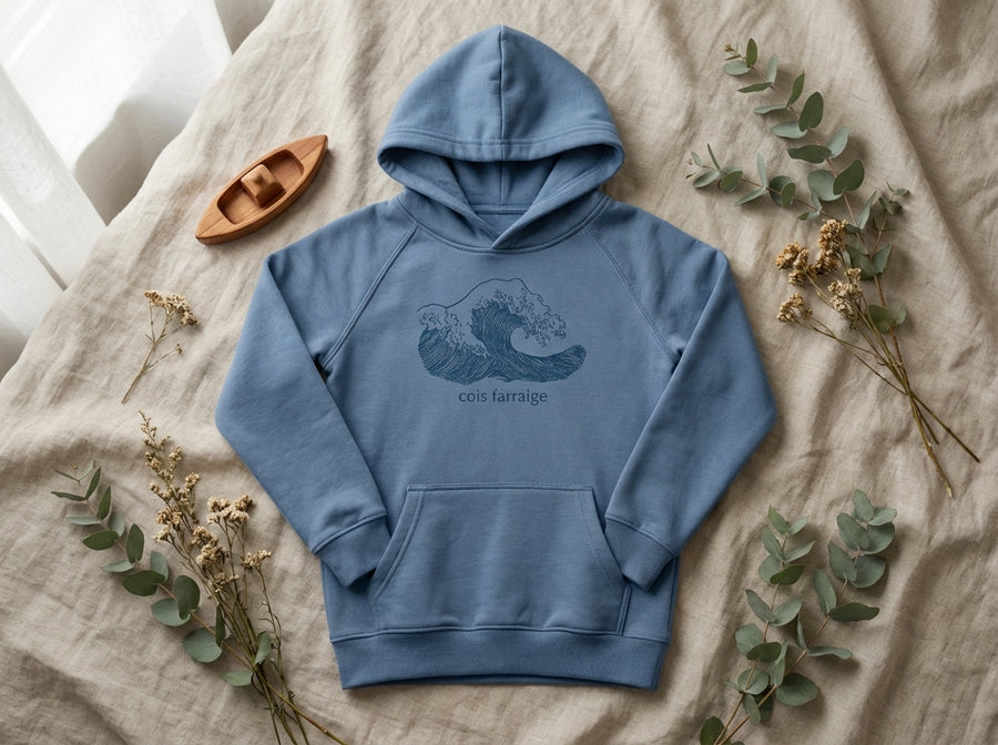 Flat lay of blue hoodie with wave design on natural leaf background