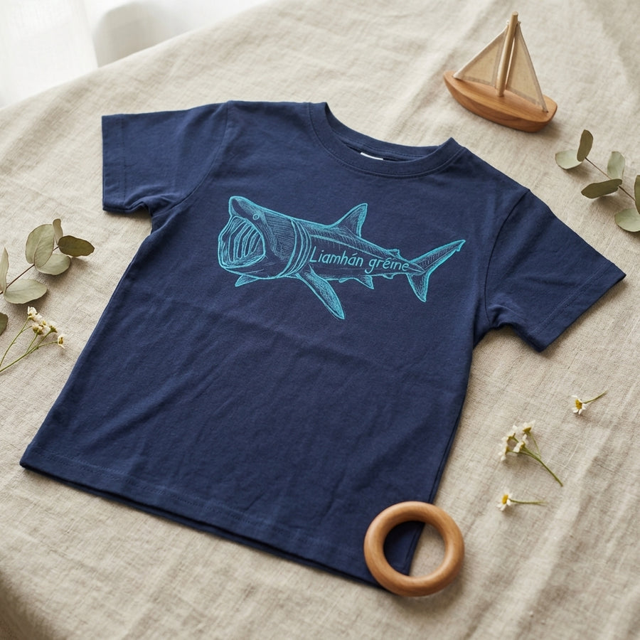 Flat lay of blue t-shirt with shark design on natural leaf background