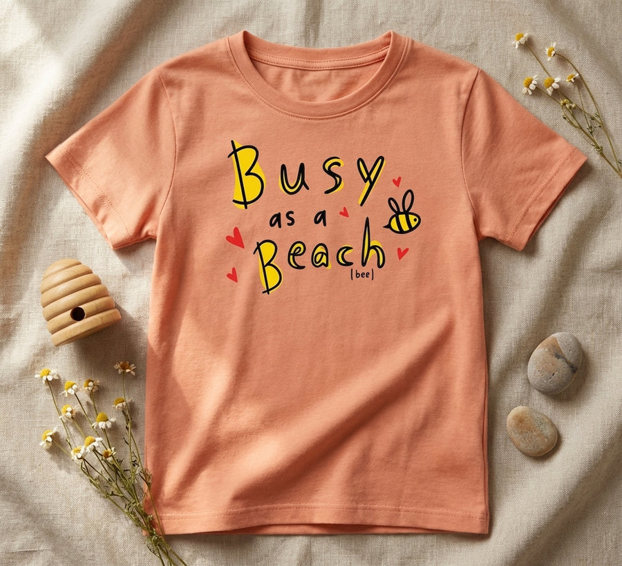 Flat lay of peach t-shirt with bee design on natural leaf background