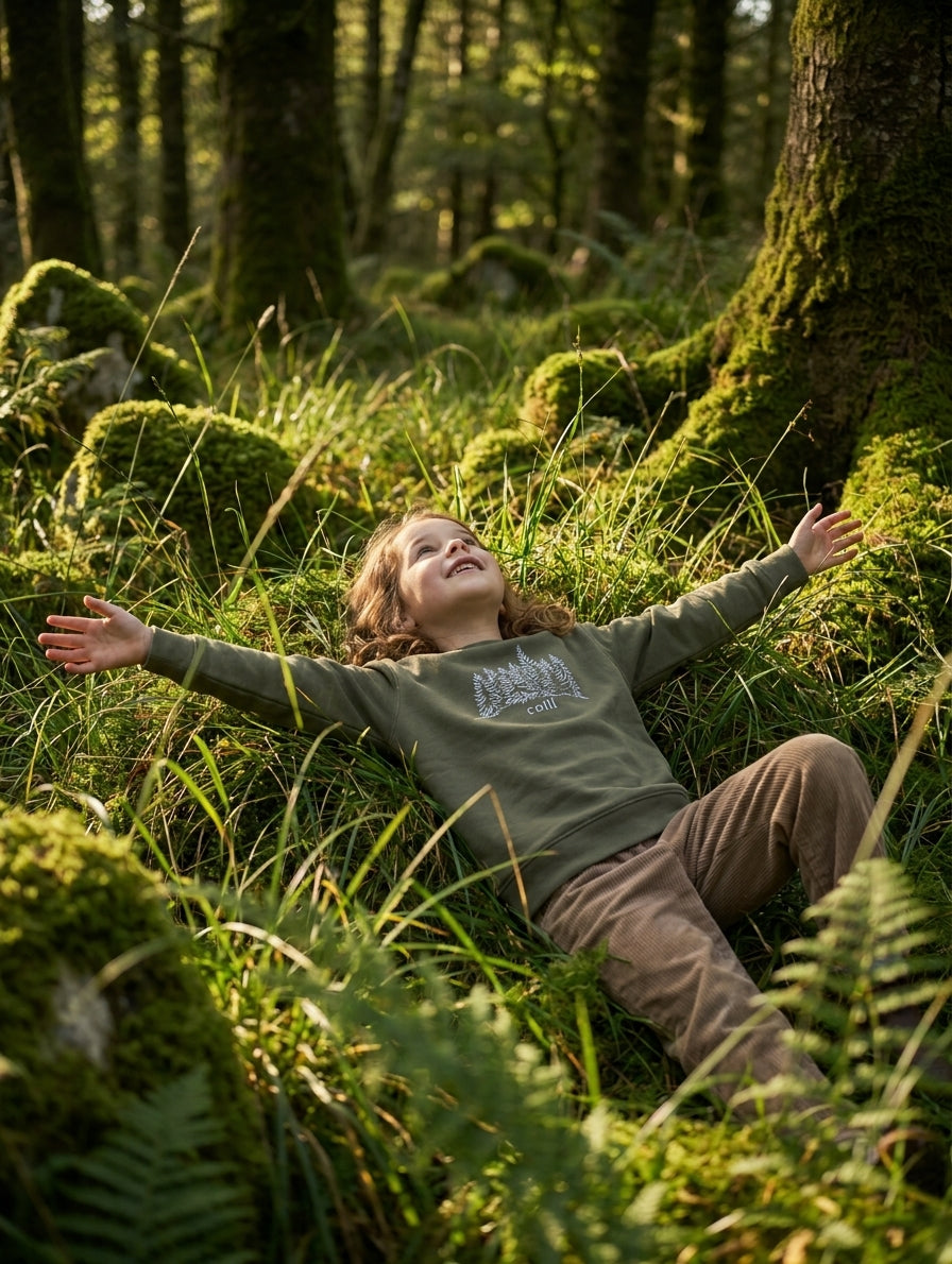 Styled editorial photo of olive kids sweatshirt with trees illustration