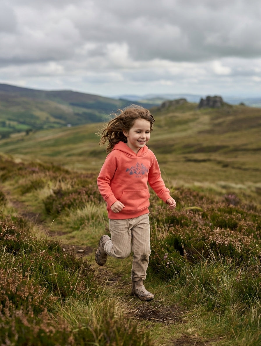 Child in motion wearing orange hoodie with mountain design