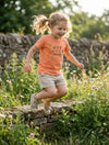 Child in motion wearing peach t-shirt with bee design