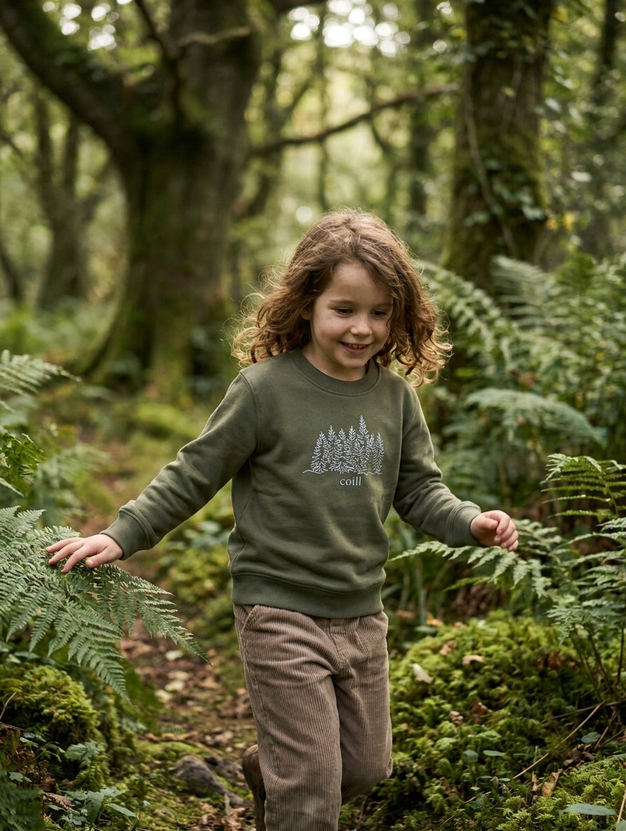 Child in motion wearing olive sweatshirt with trees design