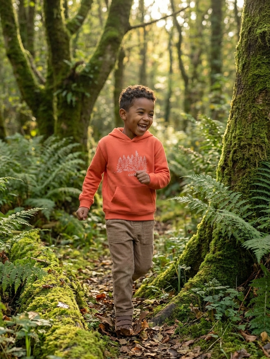 Child in motion wearing orange hoodie with trees design