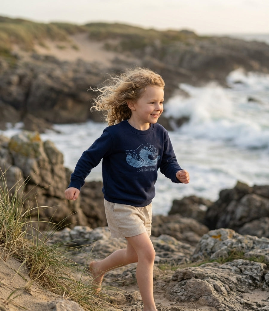 Child in motion wearing navy sweatshirt with wave design