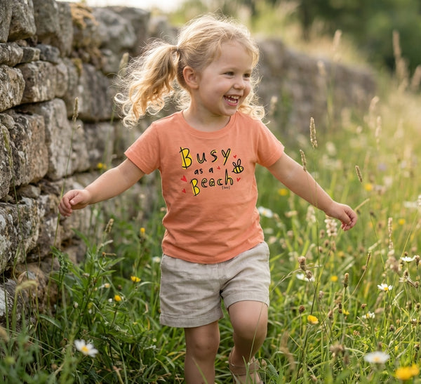 Child in motion wearing peach t-shirt with bee design