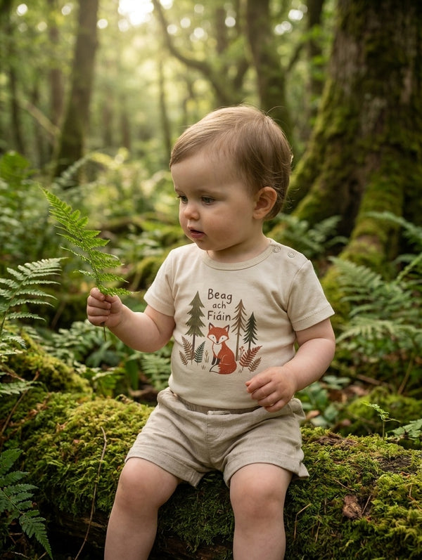Child wearing cream bodysuit with beagfiain design, portrait