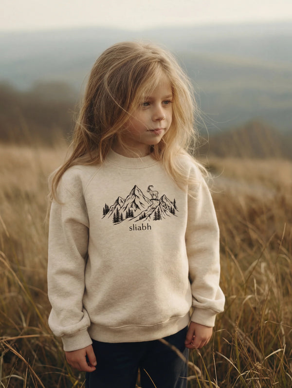 Child wearing beige sweatshirt with mountain design, portrait