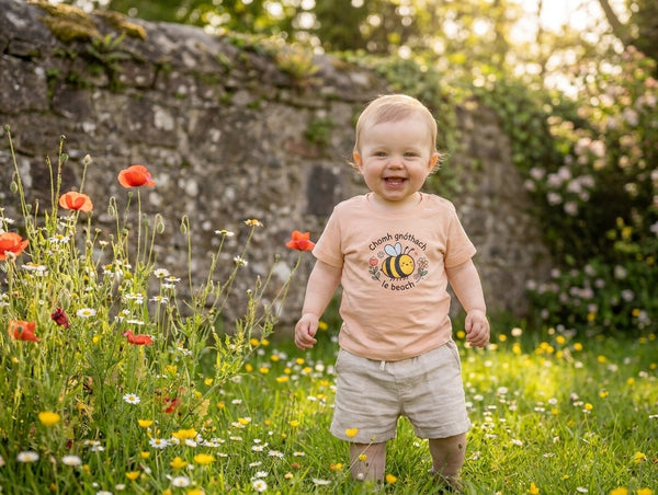 Child wearing peach t-shirt with bee design, portrait