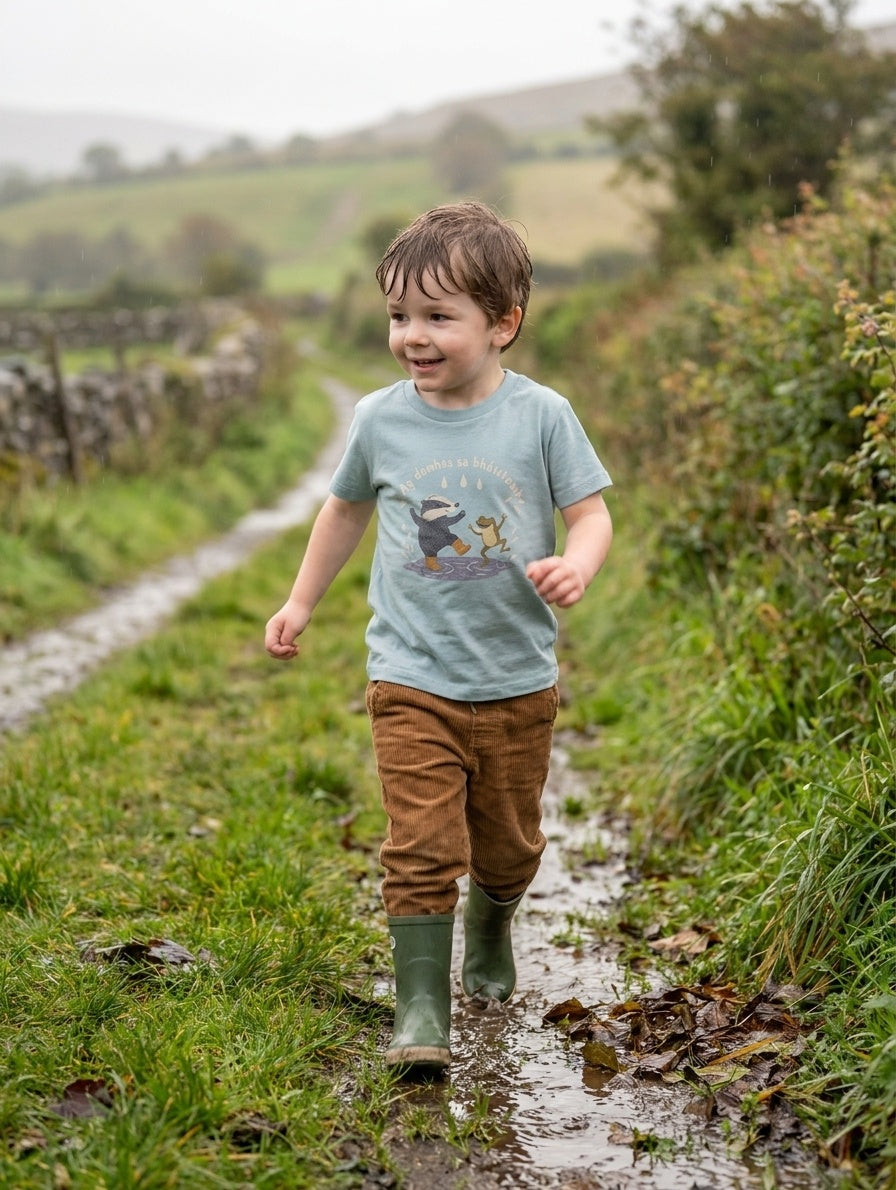 Child wearing seafoam t-shirt with badger-frog design, portrait
