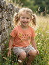 Child wearing peach t-shirt with bee design, portrait