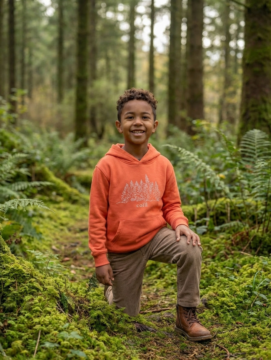 Child wearing orange hoodie with trees design, portrait