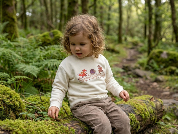 Child wearing cream sweatshirt with spraoisachoill design, portrait