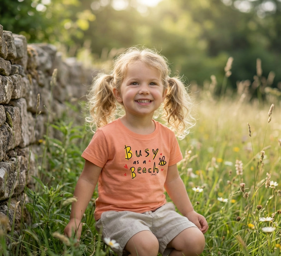 Child wearing peach t-shirt with bee design, portrait