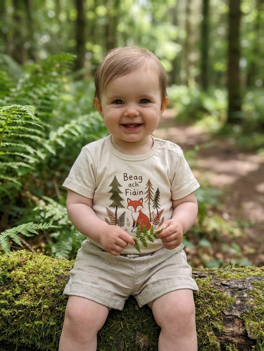 Child wearing cream bodysuit with beagfiain design, portrait