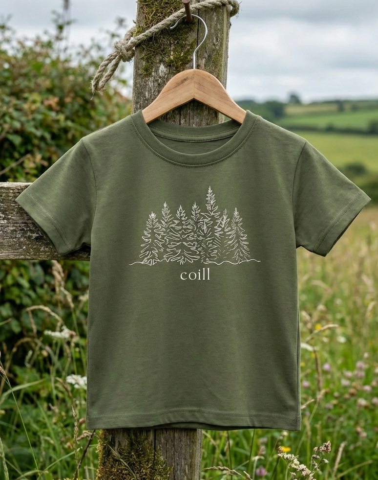 Green Coill kids t-shirt hanging on a wooden hanger on an Irish nature walk