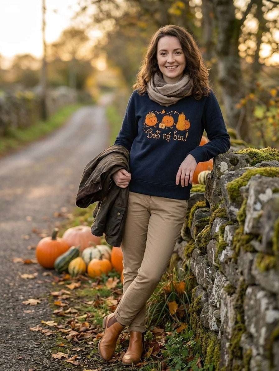 Woman wearing the navy Bob nó Bia adult sweatshirt with a scarf beside a stone wall