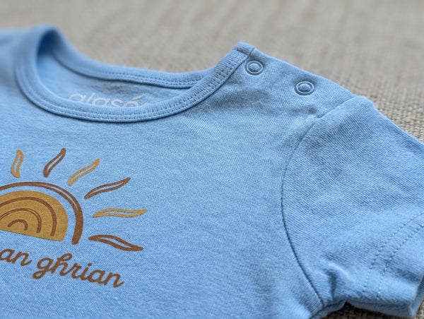 Close-up detail of sun illustration on blue bodysuit