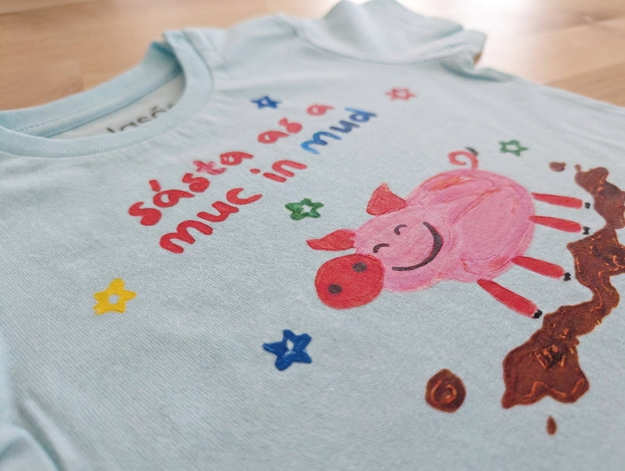 Close-up detail of pig illustration on blue baby t-shirt